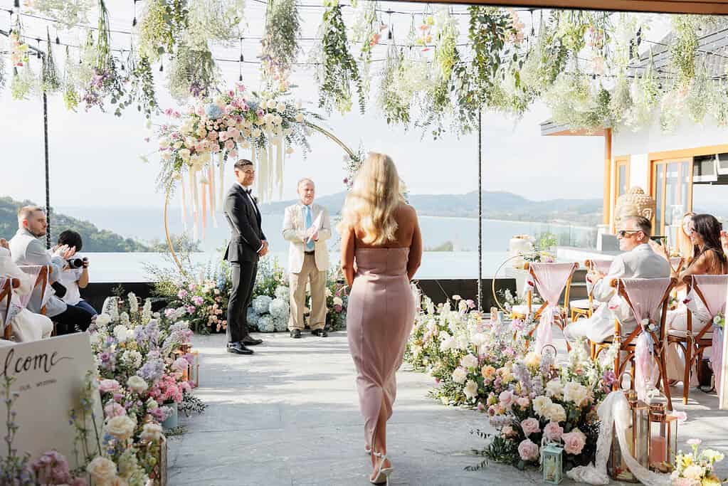A private villa wedding on Phuket — ceremony set on a clifftop lawn with the Andaman Sea beyond and the villa pool in the foreground.